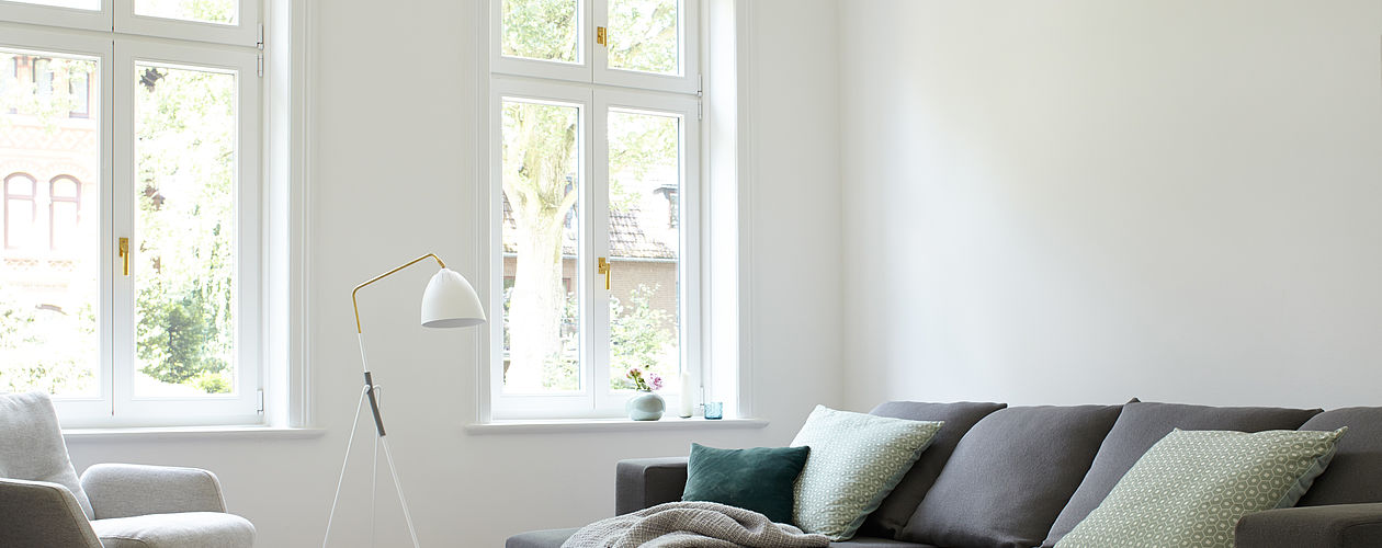 Helles, modernes Wohnimer mit grau-braunem Sofa vor einer weißen Wand. Helles, modernes Wohnimer mit grau-braunem Sofa vor einer weißen Wand.